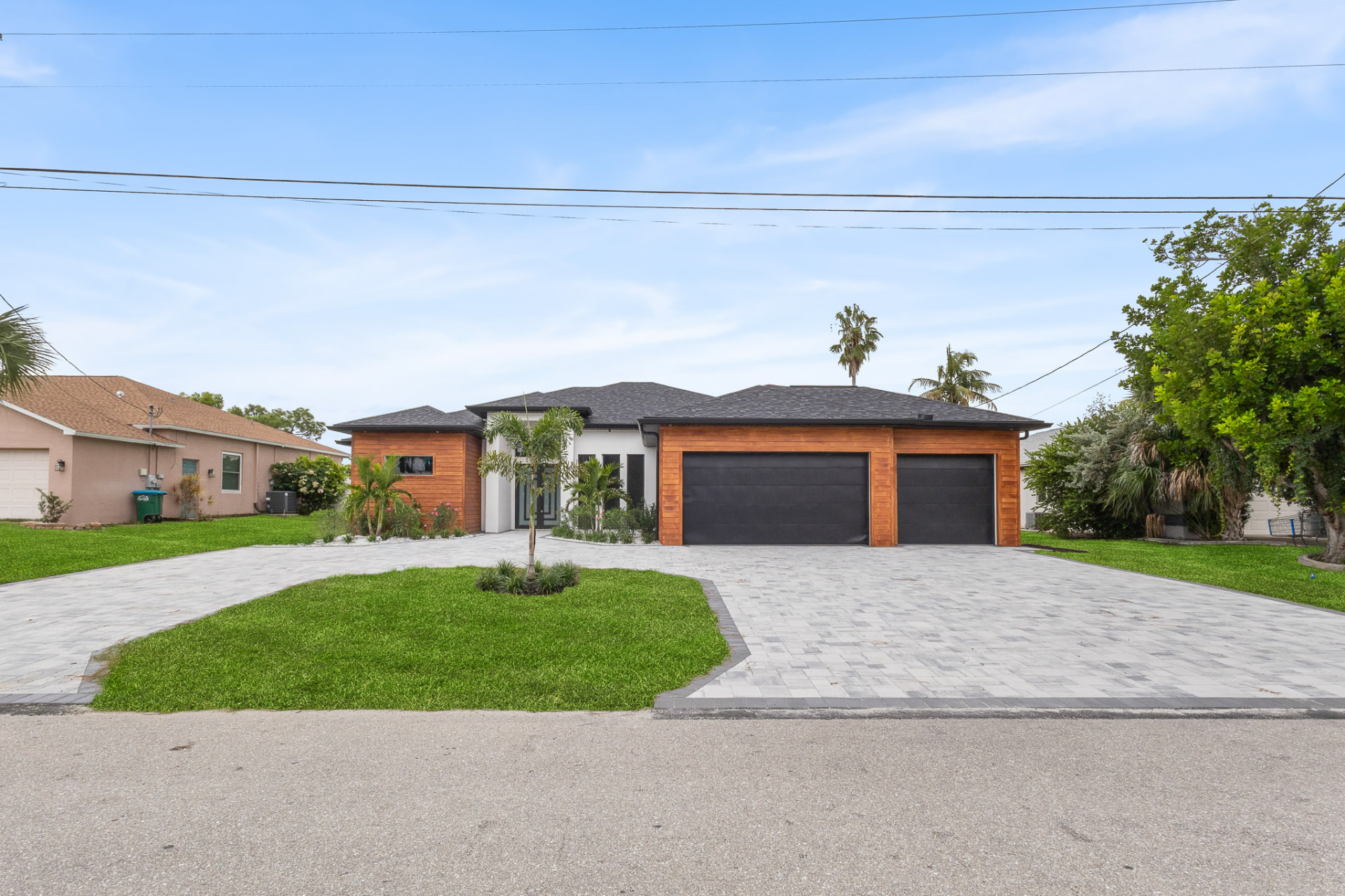 Modern Florida home with wood-accent garage doors and curved paver driveway