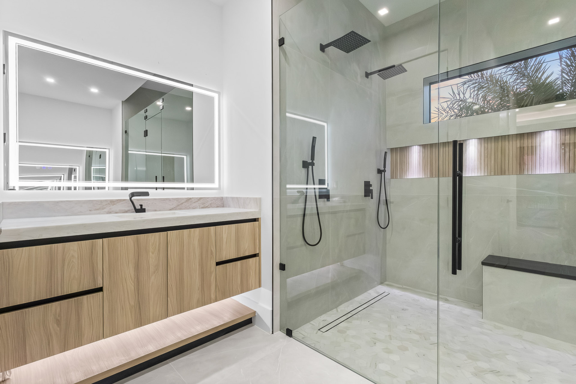 Glass-enclosed walk-in shower with backlit mirror and wood bench