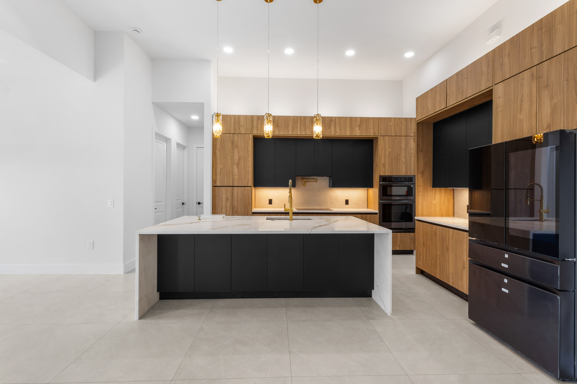 Spacious kitchen with black island, gold pendants and built-in appliances