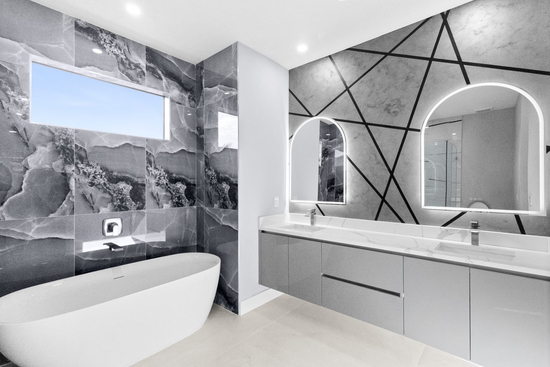 Luxury bathroom with dramatic marble walls, dual arched mirrors and freestanding tub