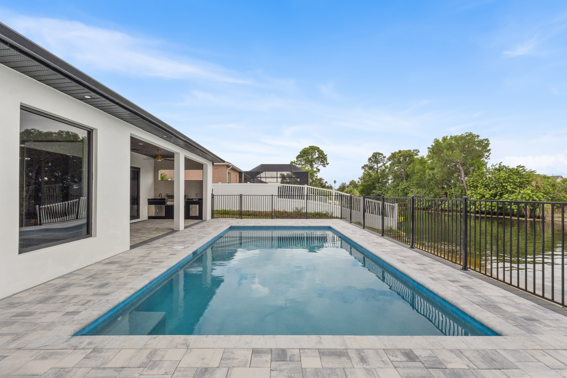 Backyard pool overlooking a lake with an outdoor kitchen