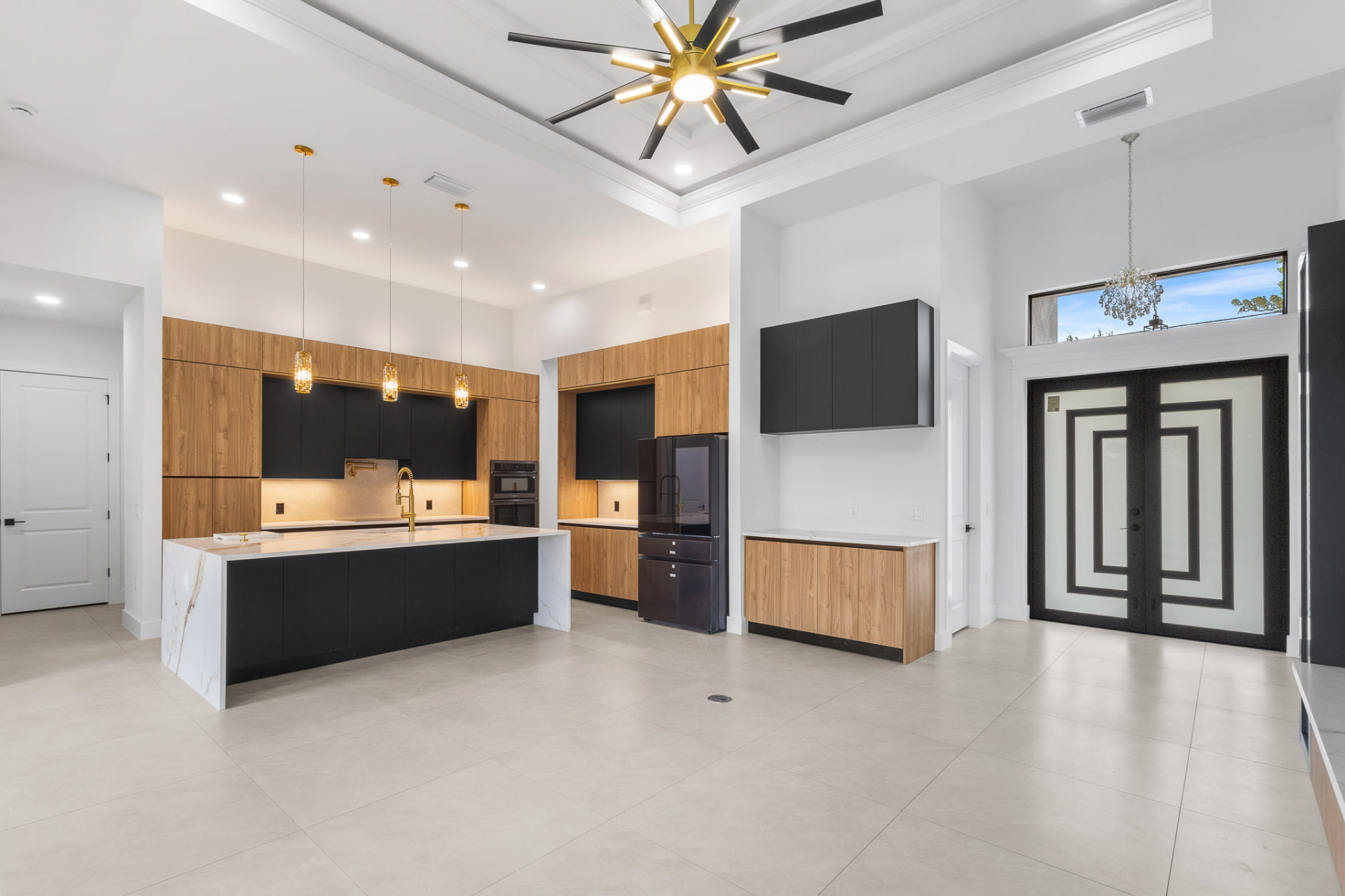 Two-tone kitchen with black island, wood cabinetry and brass fixtures