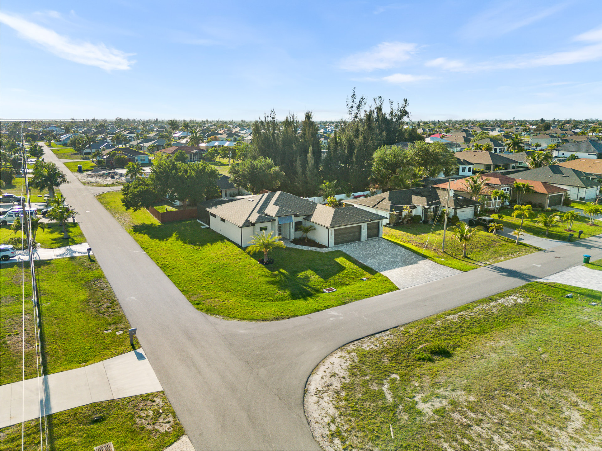 Aerial drone view of a corner-lot home on a quiet residential street