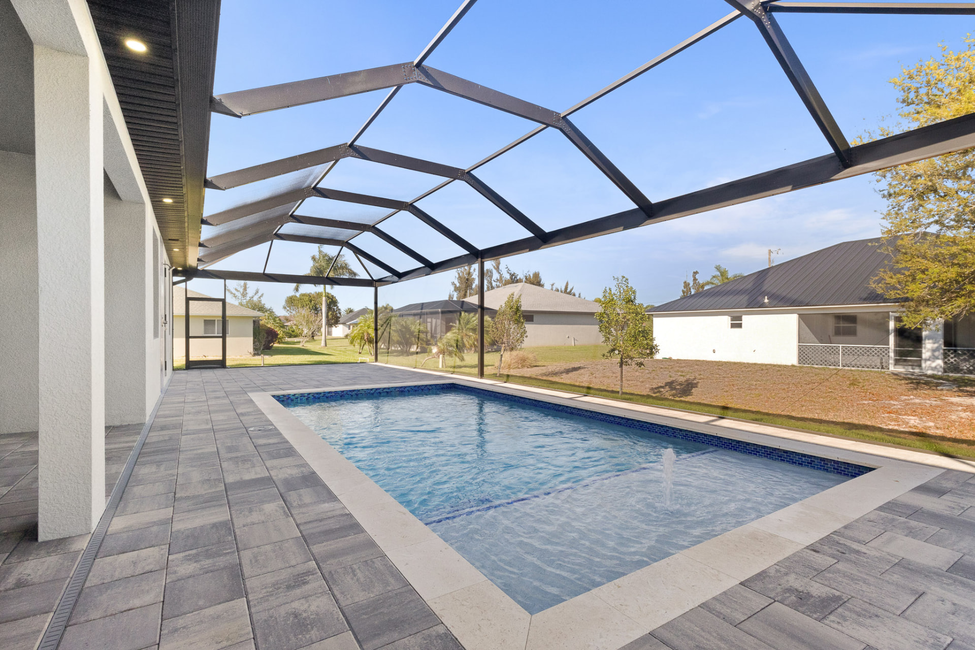 Pool under a screened enclosure with a tiled deck
