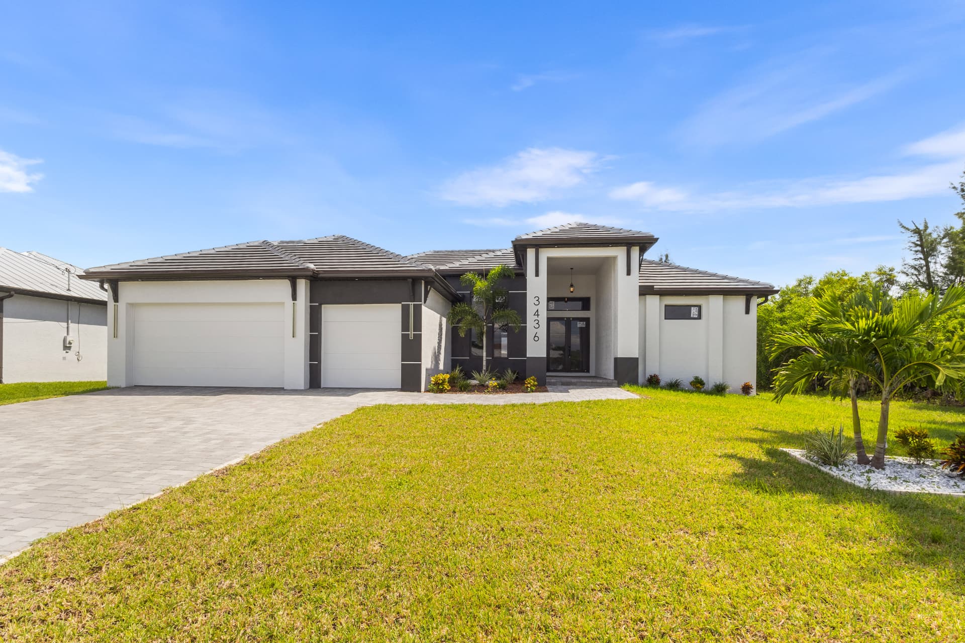White stucco home with tile roof and palm trees under a blue sky
