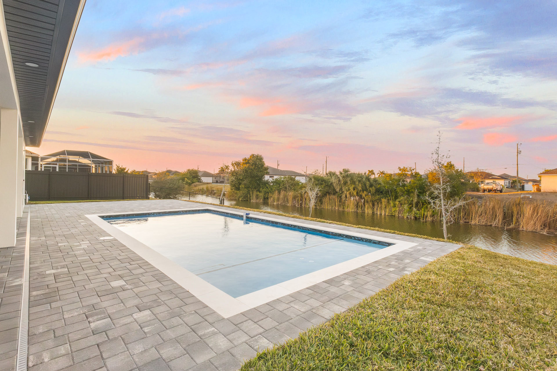 Pool and lake at sunset under a pink sky
