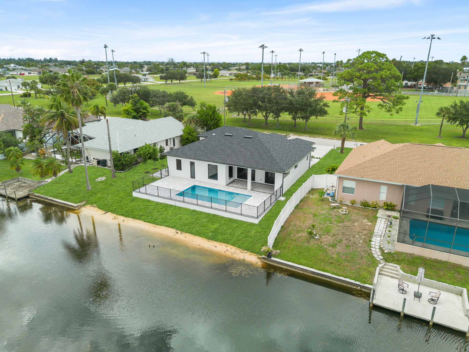 Aerial drone view of a waterfront home with pool and dock
