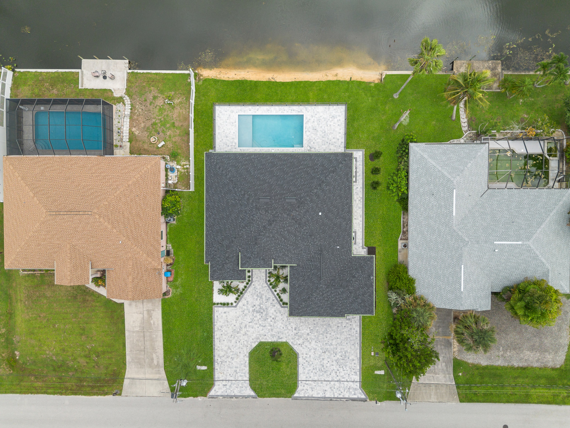 Top-down drone view of a home, pool and neighboring canal