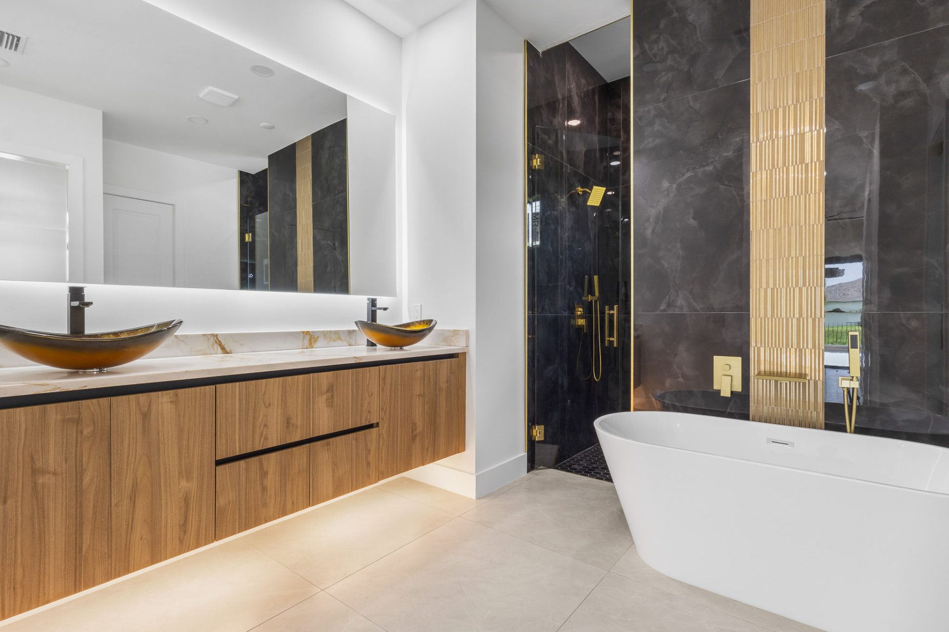 Bathroom with black marble shower, gold accents and glass vessel sinks