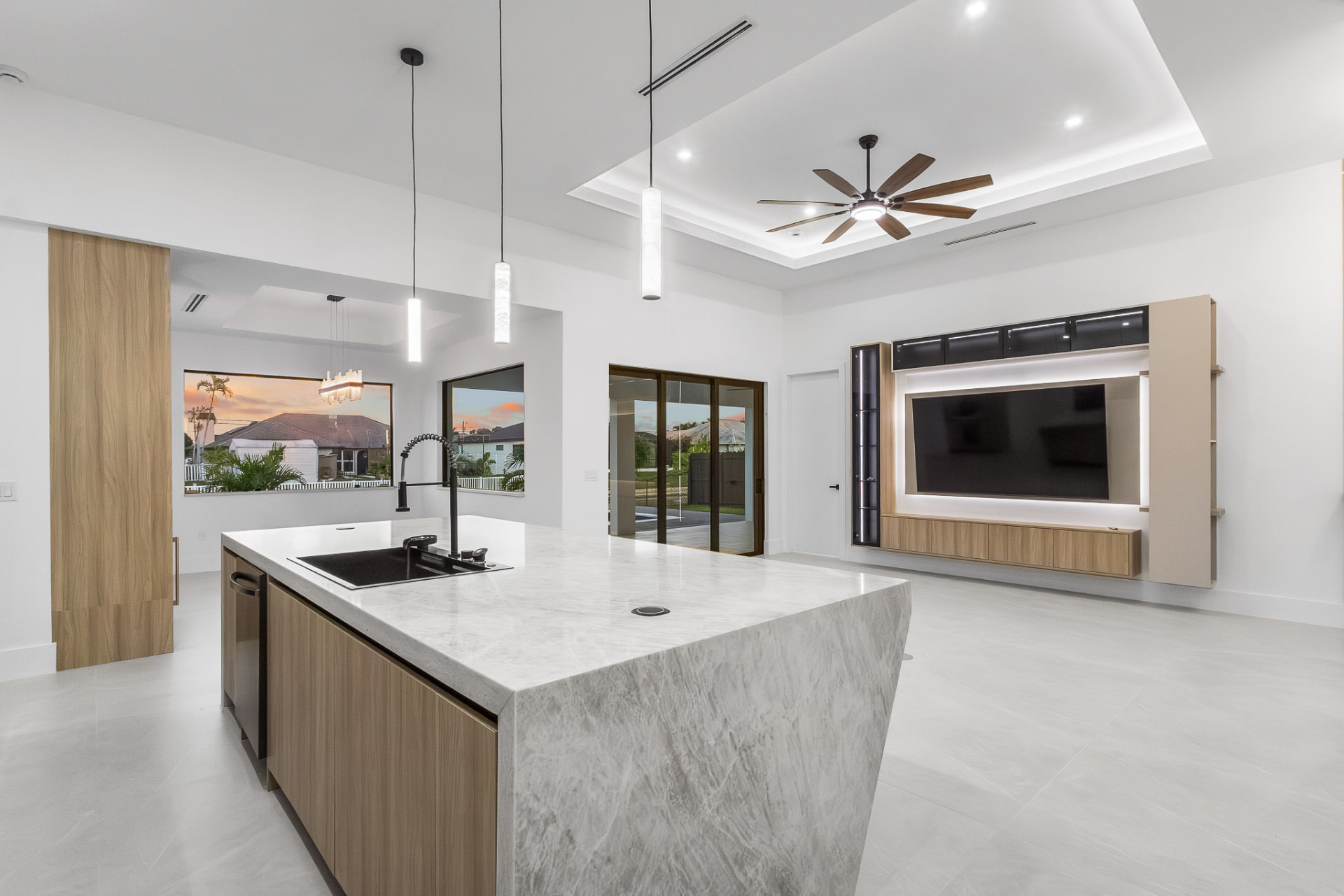 Gourmet kitchen with marble island and custom media wall with backlit shelves