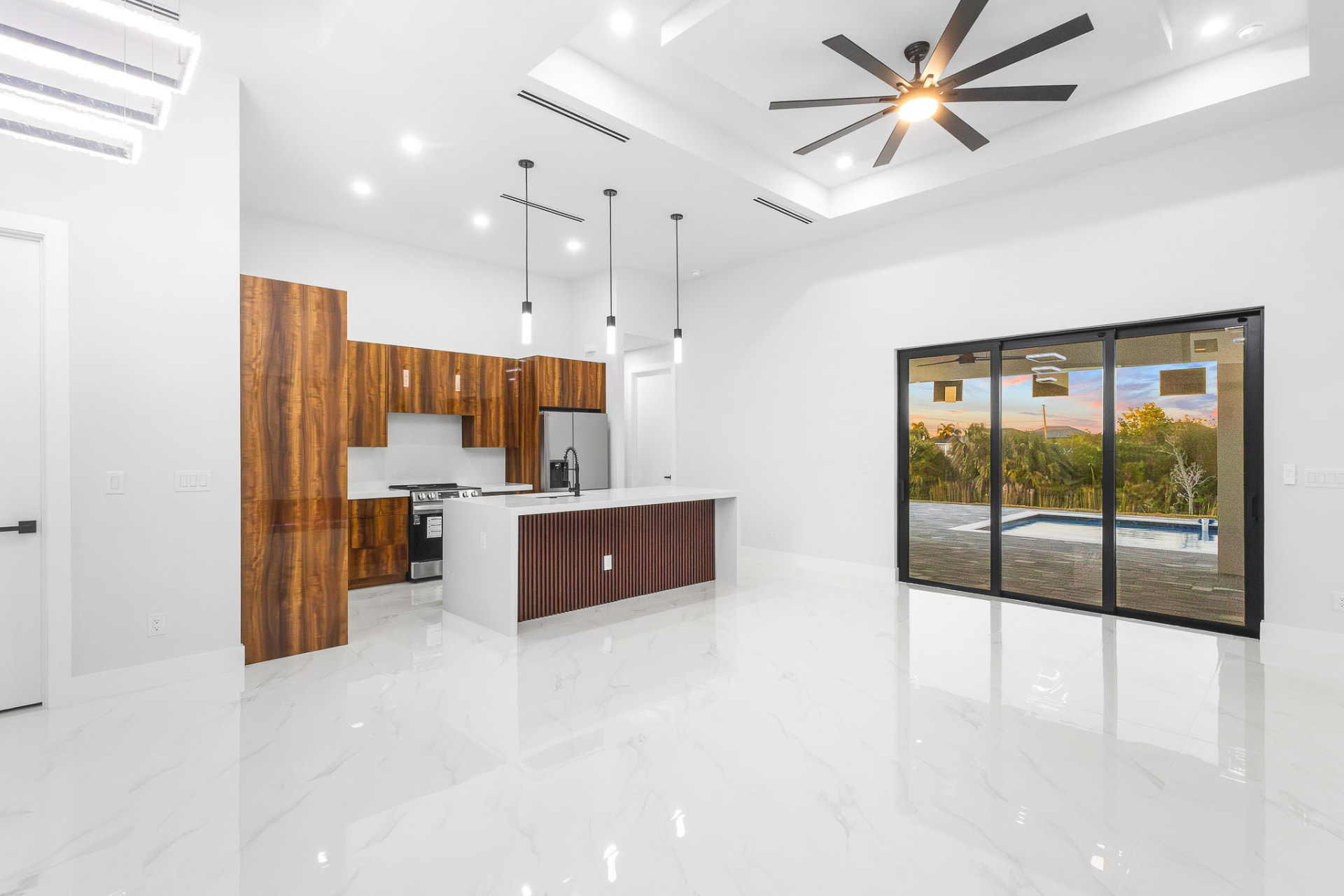 Bright kitchen with wood cabinetry opening to a pool and sunset views